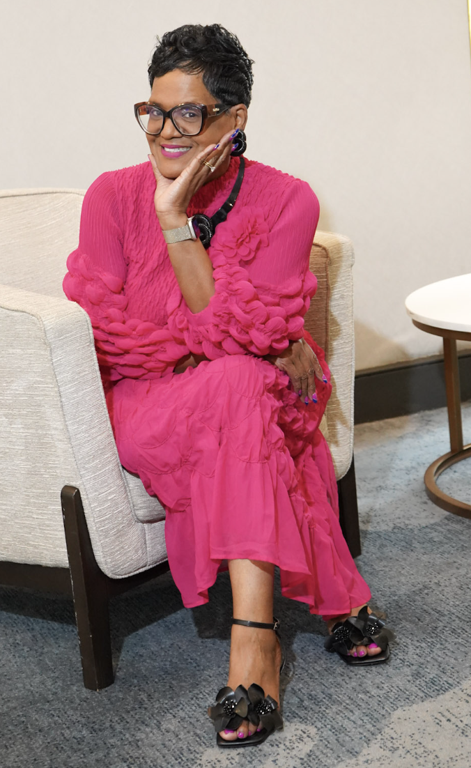 Dr. Lucretia seated in a pink dress, smiling
