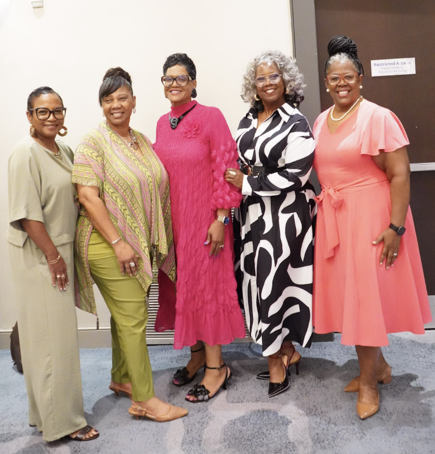 Dr. Lucretia surrounded by five women in bright attire